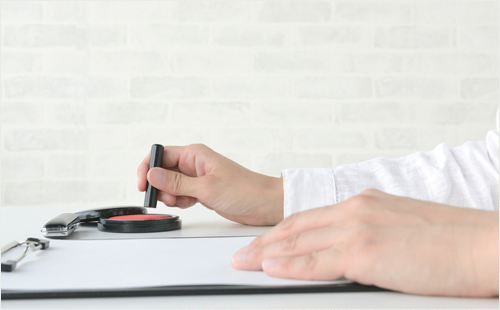 契約書に捺印する人物の手